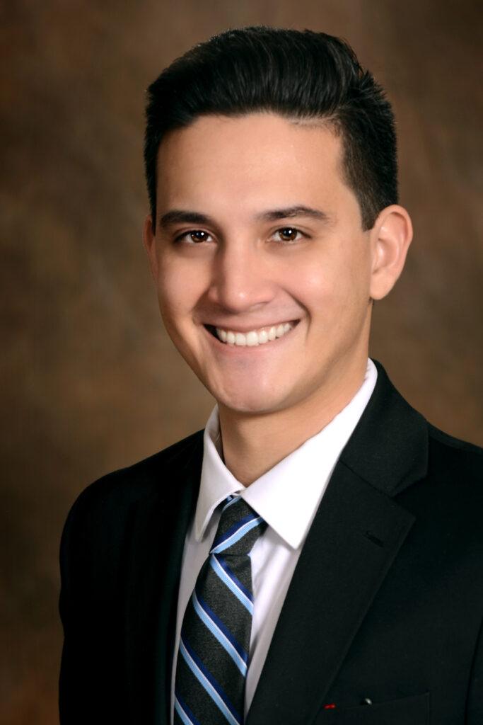 A professional headshot of Attorney Kenneth Chiarella in a Black suit jacket, white shirt and black and blue tie.